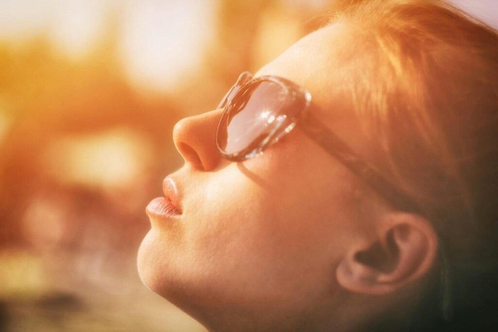 Close-up portrait of a woman with sunglasses enjoying sunlight and relaxation outdoors.