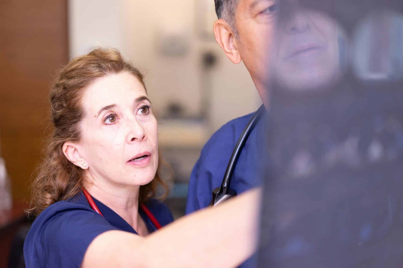 Doctors in scrubs examining an X-ray in a clinical setting for diagnosis.
